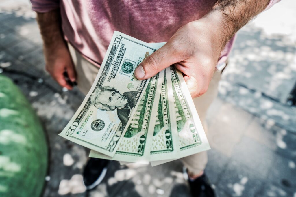 20k a month: a hand holding four 20 dollar bills